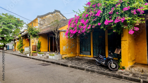 Fotografie Charming yellow building with blooming bougainvillaea on a quiet street in Hoi A
