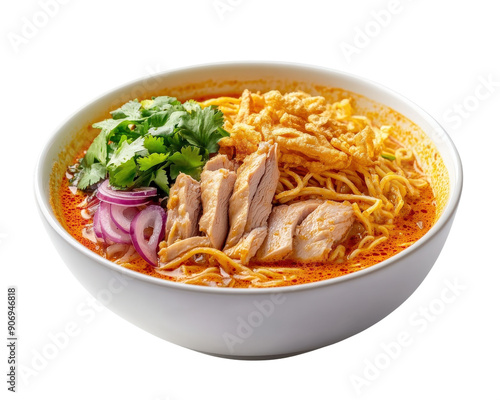 A bowl of khao soi chicken and onions and a lime on top. The soup is yellow and orange and has a lot of noodles