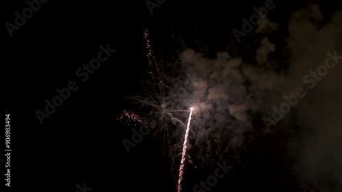 View of several fireworks rising and exploding in the dark night sky and leaving a trail of smoke. Party. Festival. Rocket.