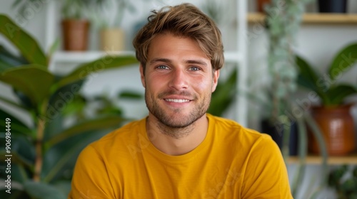 Young Man Standing Confidently Against Floral Background in Sunlit Outdoor Se...