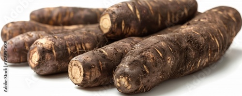 A close-up view of fresh, uncooked cassava roots displayed on a white background, highlighting the texture and natural appearance of this starchy tuber often used in various culinary dishes photo