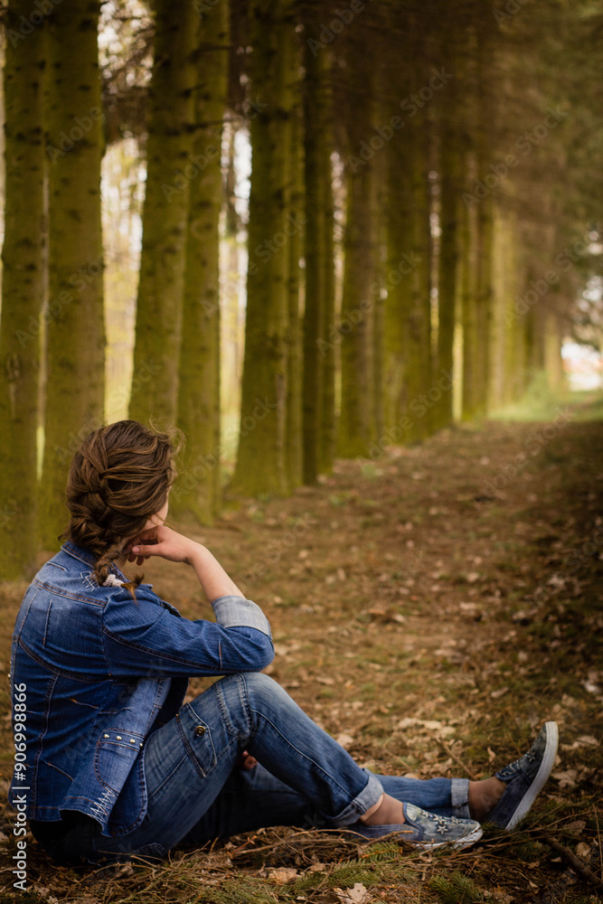 young woman sitting at the alley between the fir trees. walk in the forest young woman sitting at the alley between the fir trees. walk in the forest
