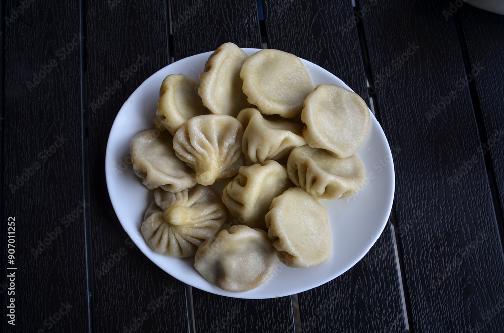 Delicious georgian dumplings khinkali pinched at the top flavorful meat filling inside served on a white plate, on a dark wooden surface. Perfect for food blogs, recipe websites, and culinary content Delicious georgian dumplings khinkali pinched at the top flavorful meat filling inside served on a white plate, on a dark wooden surface. Perfect for food blogs, recipe websites, and culinary content
