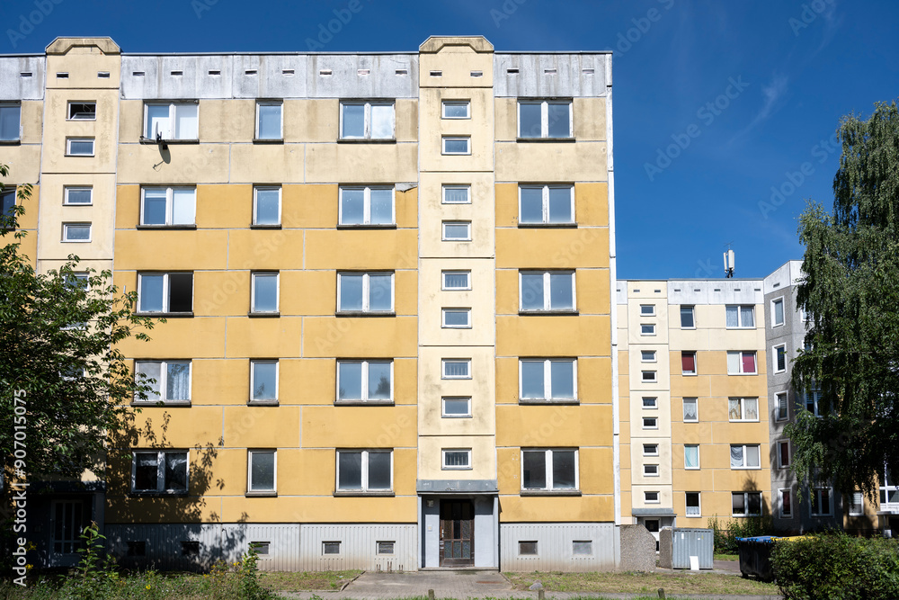 Older high-rise apartment block for social housing with yellow cladding against a blue sky, large panel system building in Schwerin, Germany, architecture concept Older high-rise apartment block for social housing with yellow cladding against a blue sky, large panel system building in Schwerin, Germany, architecture concept