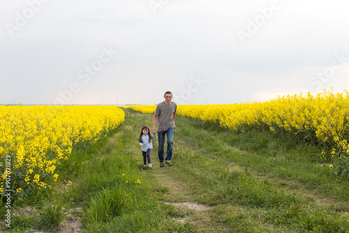 father and daughter running through a blooming field. playing with parents, upbringing, happiness of being a father