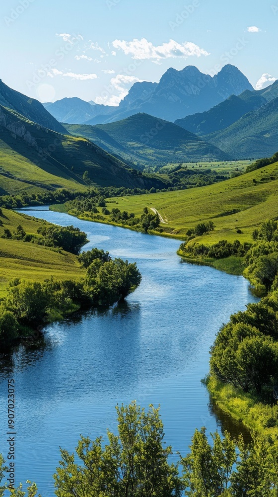 Fototapeta premium Sweeping Panorama of a River Surrounded by Lush Green Mountains on a Sunny Day, Embracing Nature's Serene Grandeur