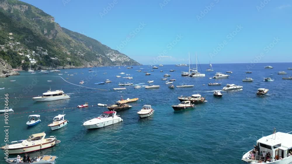 Positano in the Amalfi coast, Salerno, Campania region - Italy.Tourist season. High angle view of boats moored. Luxury yachts, boats on Tyrrhenian Sea. Bright sunny day. Copy space. Aerial view Positano in the Amalfi coast, Salerno, Campania region - Italy.Tourist season. High angle view of boats moored. Luxury yachts, boats on Tyrrhenian Sea. Bright sunny day. Copy space. Aerial view