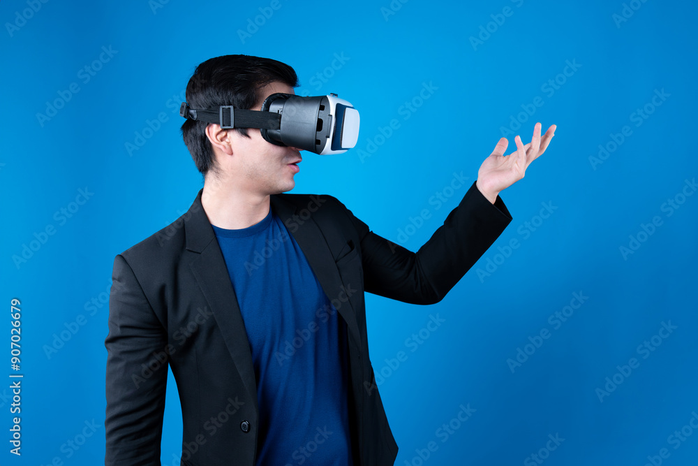 Profile of businessman wearing VR device connecting metaverse, holding stuff in the air isolated blue background futuristic analytics communication technology virtual reality copyspace. Contrivance. Profile of businessman wearing VR device connecting metaverse, holding stuff in the air isolated blue background futuristic analytics communication technology virtual reality copyspace. Contrivance.