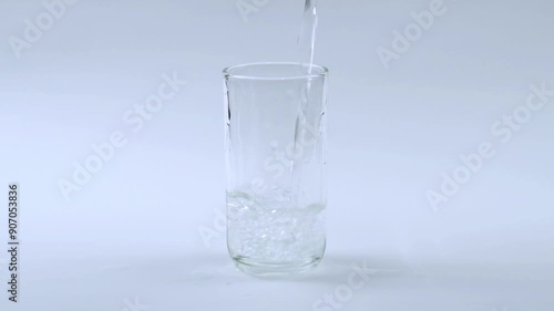 pouring drinking water into glass with white background slow motion