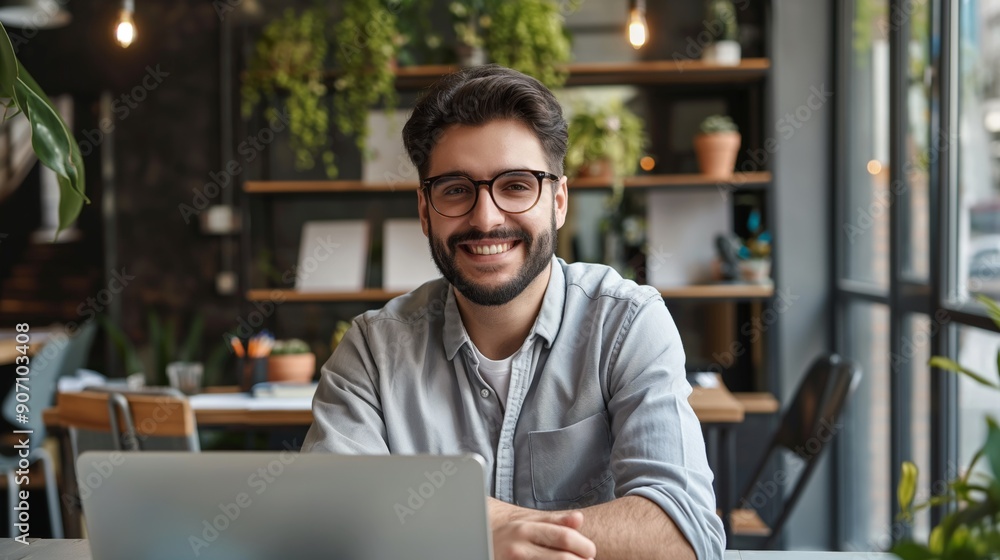 Fototapeta premium Portrait of happy young businessman working on his laptop