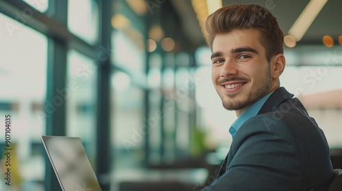 Portrait of happy young businessman working on his laptop