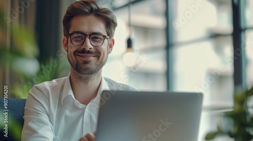 Portrait of happy young businessman working on his laptop