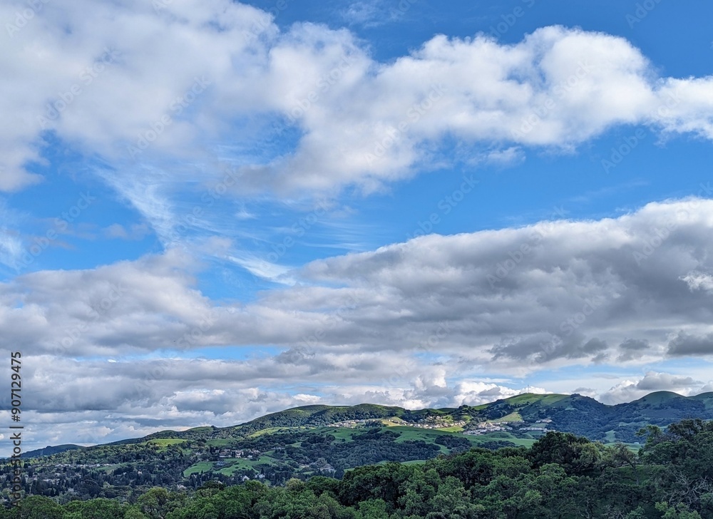 rolling green hills stretch beneath a wide azure sky, adorned with drifting clouds and dotted with charming hillside houses rolling green hills stretch beneath a wide azure sky, adorned with drifting clouds and dotted with charming hillside houses
