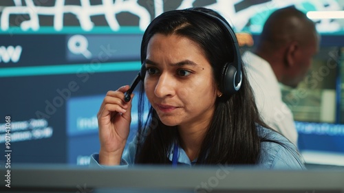 Indian woman dispatch operator gives directions to couriers, avoiding traffic by monitoring radar CCTV surveillance footage. Employee uses gps coordinates and satellite map. Camera A.