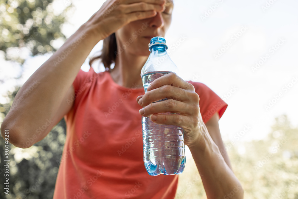 Woman suffers from heat exhaustion in the summer season holding bottle of drinking water
Woman suffers from heat exhaustion in the summer season holding bottle of drinking water