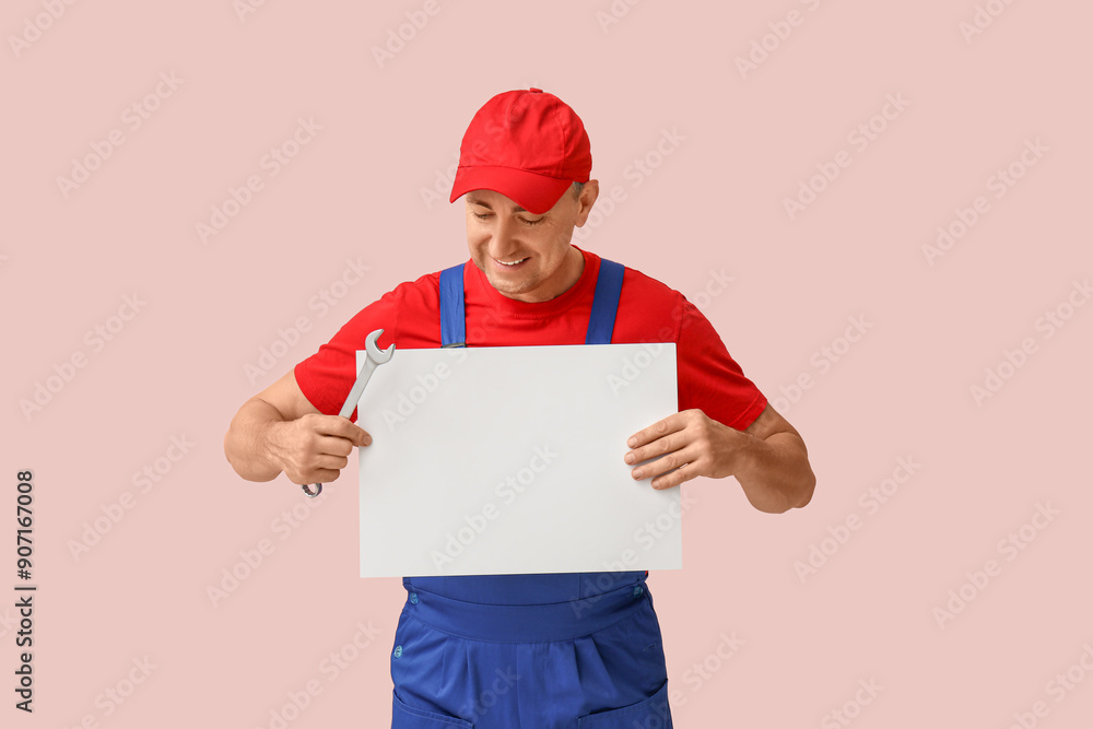 Portrait of male mechanic with blank poster on pink background Portrait of male mechanic with blank poster on pink background