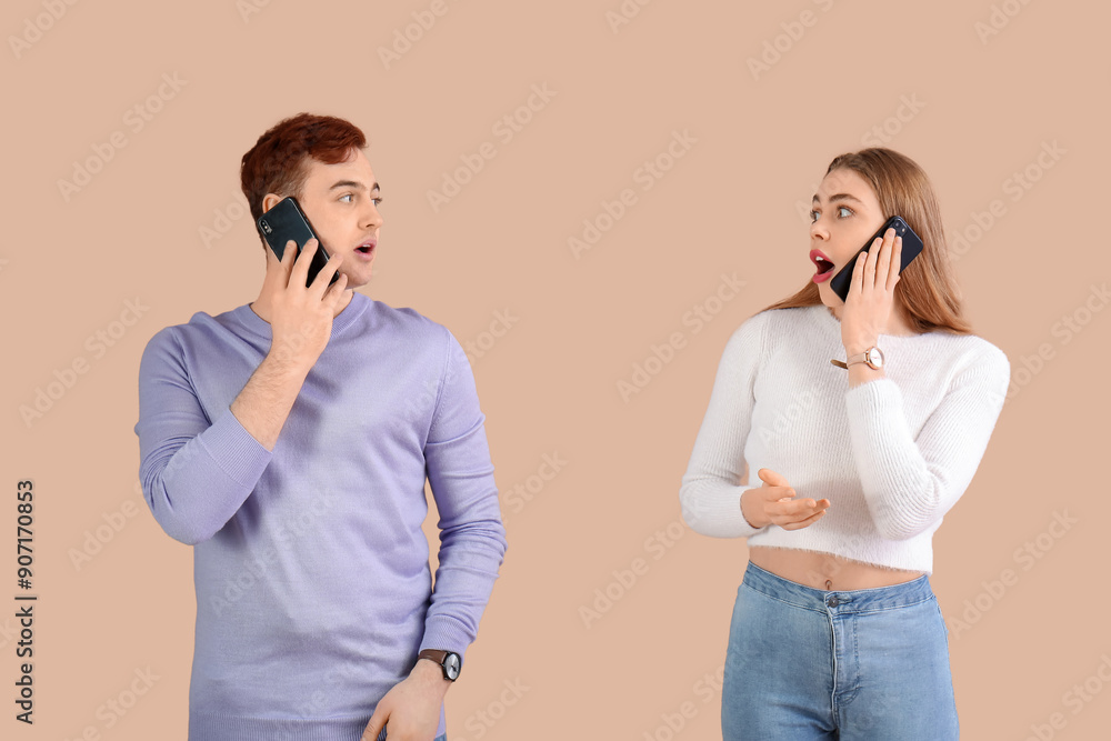Shocked young couple with mobile phones on brown background Shocked young couple with mobile phones on brown background