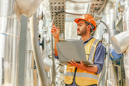 Canvas Print Male HAVC refrigeration system technician stands holding laptop recording preventative inspection refrigeration equipment refrigerant level control valve into the system and checking leaks at various