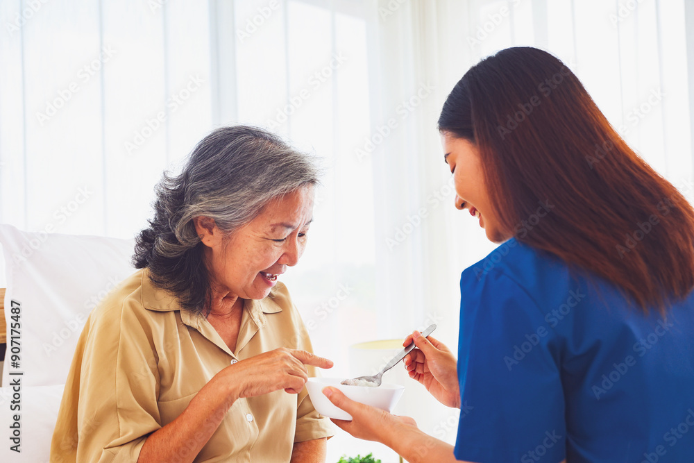 Sick elderly woman was closely cared female nurse she gently scooped nutritious, soft food porridge suitable elderly patients sick person likes eat it helping recover from her illness in bed at home. Sick elderly woman was closely cared female nurse she gently scooped nutritious, soft food porridge suitable elderly patients sick person likes eat it helping recover from her illness in bed at home.