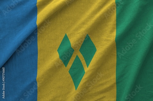 Saint Vincent and the Grenadines flag depicted on folded wavy fabric of old cloth close up photo