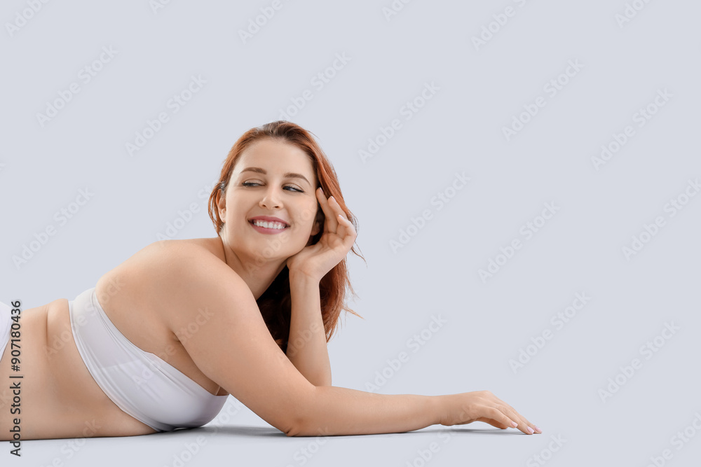 Beautiful plus size woman in underwear lying on light background Beautiful plus size woman in underwear lying on light background