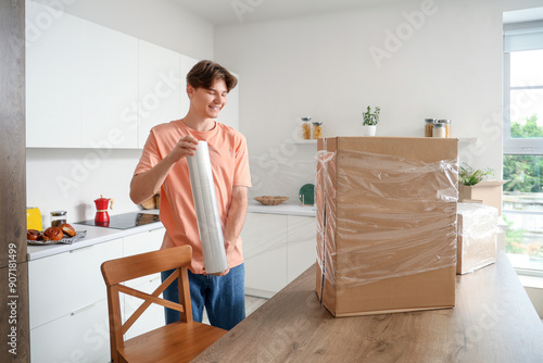 Young man wrapping cardboar...
