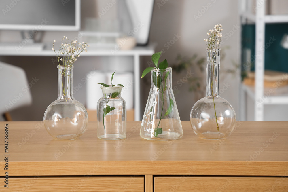 Lab flasks with green leaves and flowers on table in modern laboratory, closeup. Ecology concept Lab flasks with green leaves and flowers on table in modern laboratory, closeup. Ecology concept