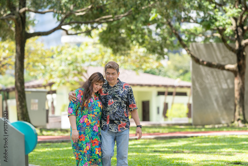 Malay man in his 50s wearing colorful shirt and Chinese woman in her 30s, walking closely together in KLCC Park in Kuala Lumpur, Malaysia. photo