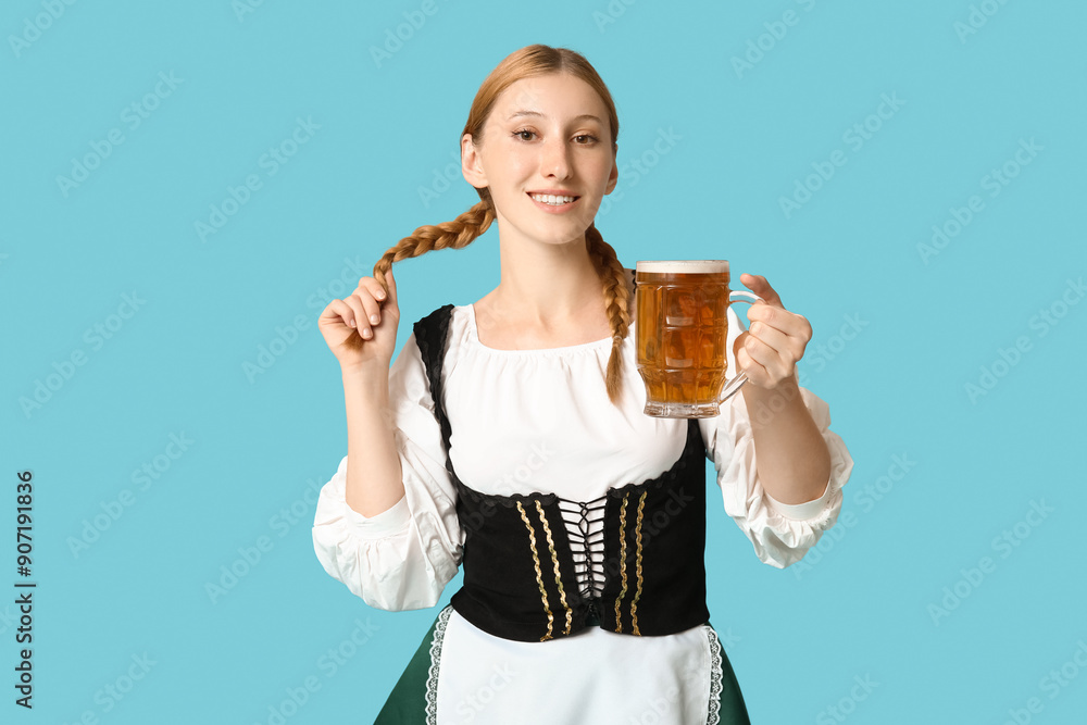 Beautiful happy Octoberfest waitress with mug of beer on blue background Beautiful happy Octoberfest waitress with mug of beer on blue background