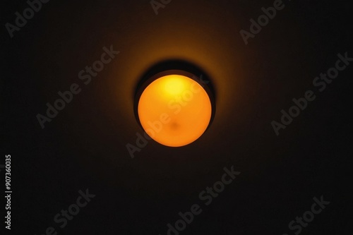 Warm orange LED lamp in the ceiling on a dark background in the center of the frame, bottom view.