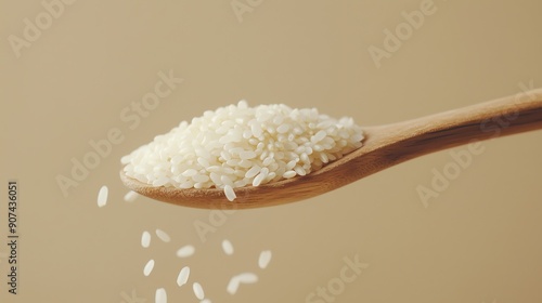 Close-up of raw white rice grains overflowing from a wooden spoon against a neutral background. photo