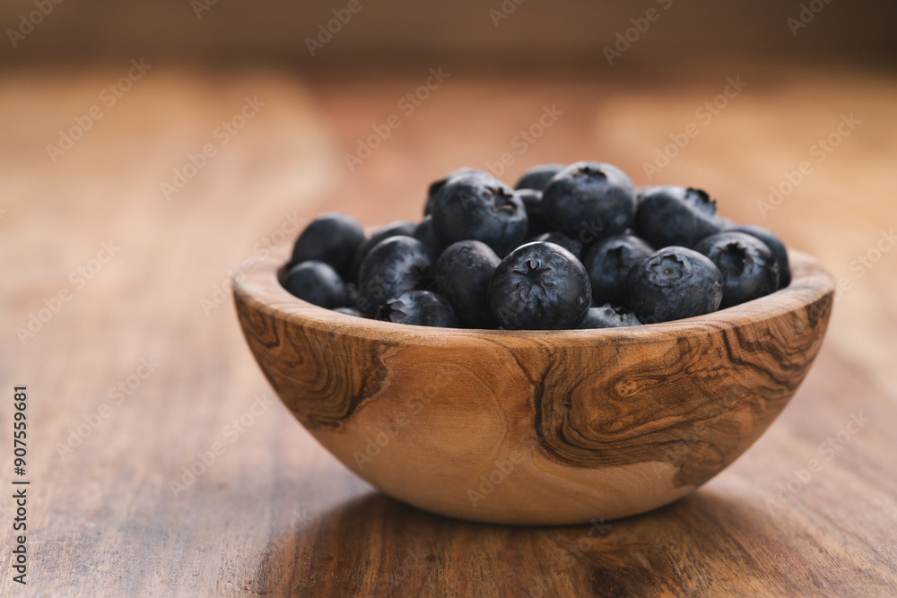 Fresh blueberries in wood bowl on table slightly toned Fresh blueberries in wood bowl on table slightly toned