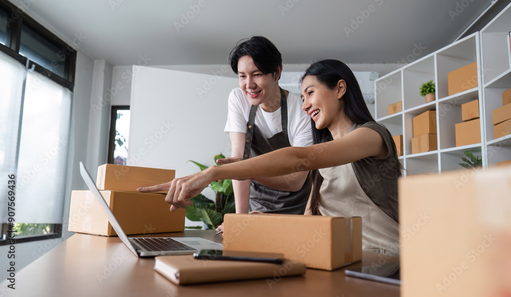 Young Couple Working Together on Their Online Business from Home Office, Surrounded by Packaging Boxes and Laptop Young Couple Working Together on Their Online Business from Home Office, Surrounded by Packaging Boxes and Laptop