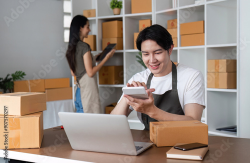 Young Couple Running an Online Business from Home, Working Together in a Modern Room Surrounded by Boxes and Technology photo