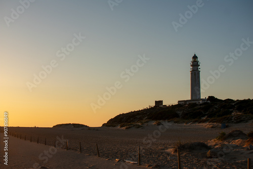 sunset over the trafalgar dunes crowned by the imposing mozarabic lighthouse of trafalgar.