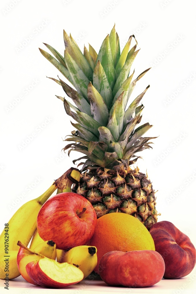 Assorted fresh fruits displayed artistically on a light background with pineapple, bananas, apples, and orange Assorted fresh fruits displayed artistically on a light background with pineapple, bananas, apples, and orange