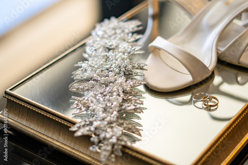 A timeless and classic bridal image featuring white shoes, gold bands, and a sparkling tiara