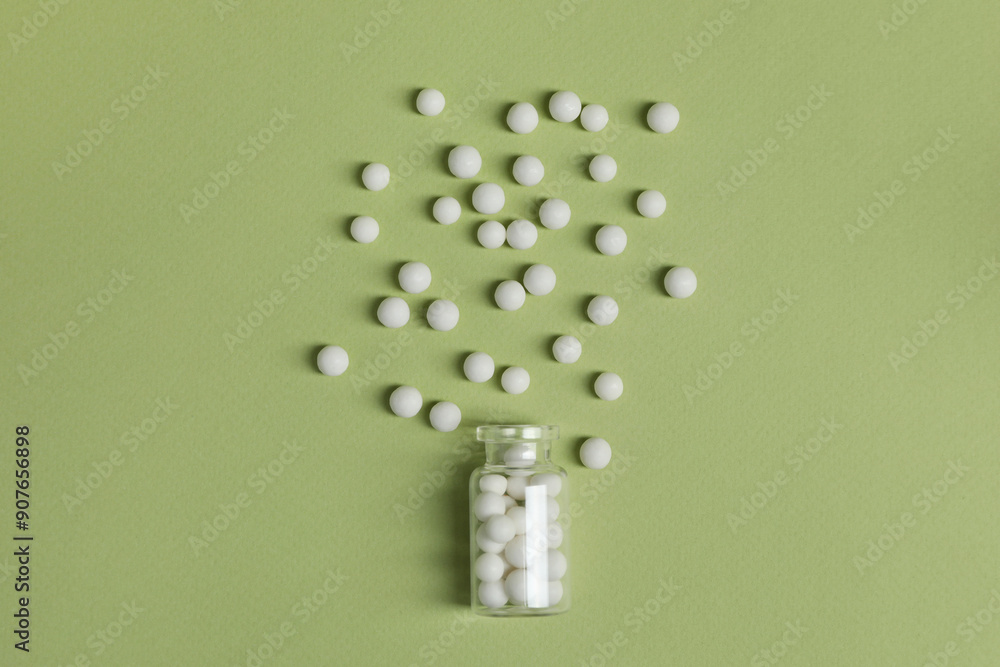 Bottle of homeopathic remedy on light green background, flat lay Bottle of homeopathic remedy on light green background, flat lay
