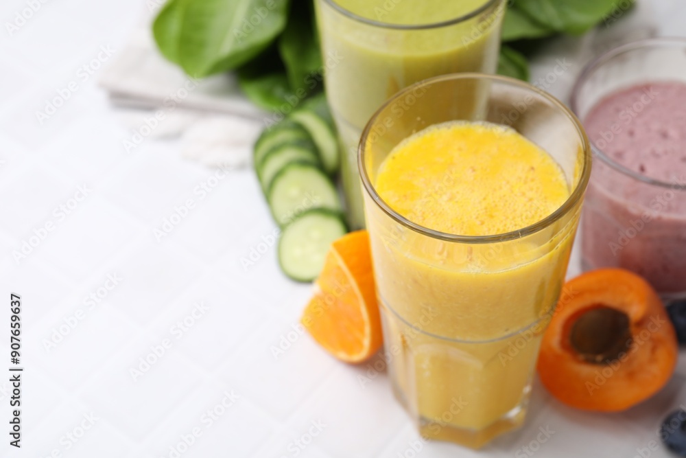 Tasty smoothies in glasses and ingredients on white tiled table, closeup. Space for text Tasty smoothies in glasses and ingredients on white tiled table, closeup. Space for text