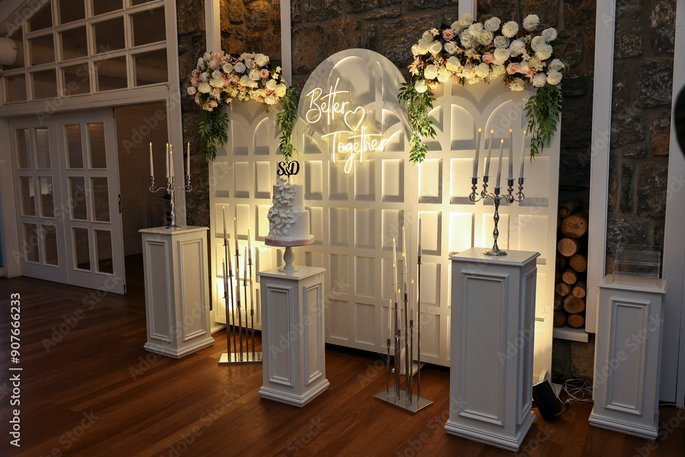 Refined Wedding Cake Presentation with Flowers and Lighting Inside Venue