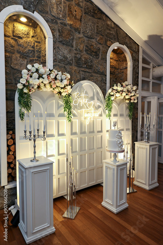 Refined Wedding Cake Presentation with Flowers and Lighting Inside Venue