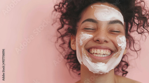 A woman with curly hair and a radiant smile indulges in a skincare routine, her face adorned with a creamy facial mask, generating a feeling of self-care and bliss. photo