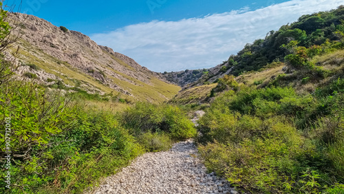 Narrow, rocky gorge Vrzenica (Žig Vrženica) cuts through rugged landscape in Baska, Krk Otok, Primorje-Gorski Kotar, Croatia. Scenic hiking trail through dramatic canyon leading to Vela and Mala Luka photo