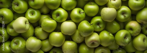 Close-up shot of a pile of green apples, the apples are arranged in a random pattern, and light shines through their skin.