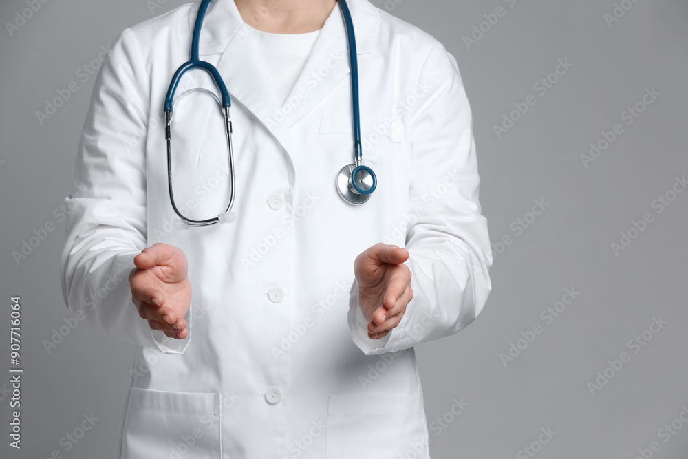 Doctor holding something on grey background, closeup. Space for text Doctor holding something on grey background, closeup. Space for text
