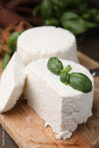 Fresh ricotta (cream cheese) and basil on wooden table, closeup