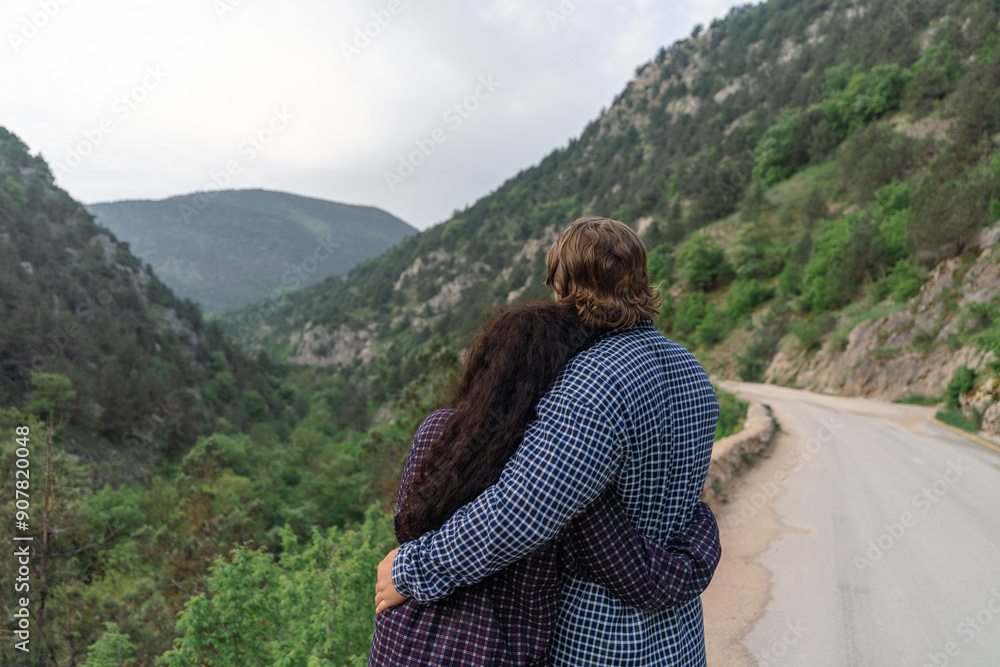 Naklejka premium A couple is hugging each other on a road in the mountains
