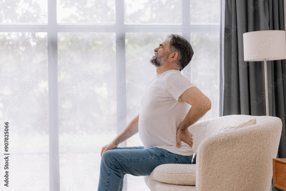 Senior man suffering from back pain on sofa at home Senior man suffering from back pain on sofa at home