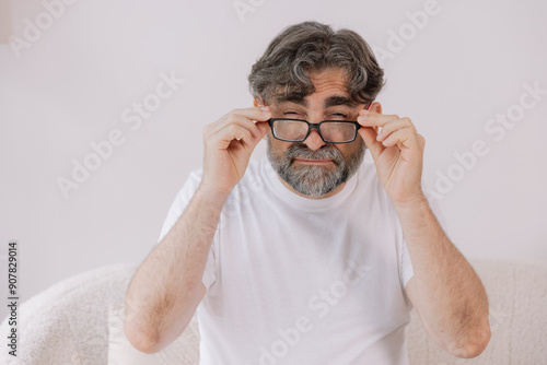 Poor Eyesight. Senior Man Can't See, Squinting Eyes Wearing Glasses Having Problems With Vision, Looking At Camera At Living Room. Ophtalmic Issue, Bad Sight In Older Age, Macular Degeneration Concept photo