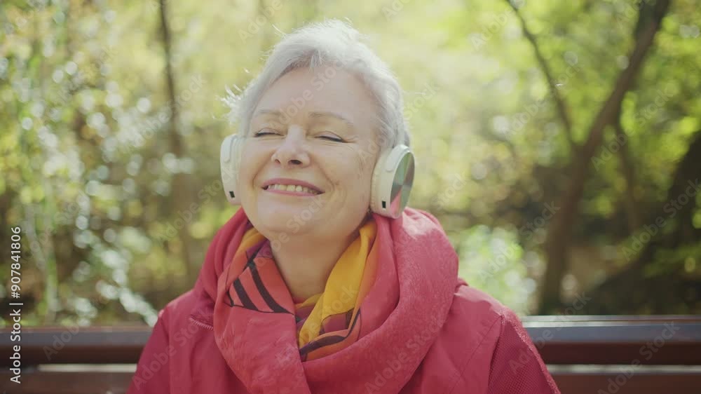 Elderly Woman Enjoys Autumn Walk in Park With Headphones Elderly Woman Enjoys Autumn Walk in Park With Headphones